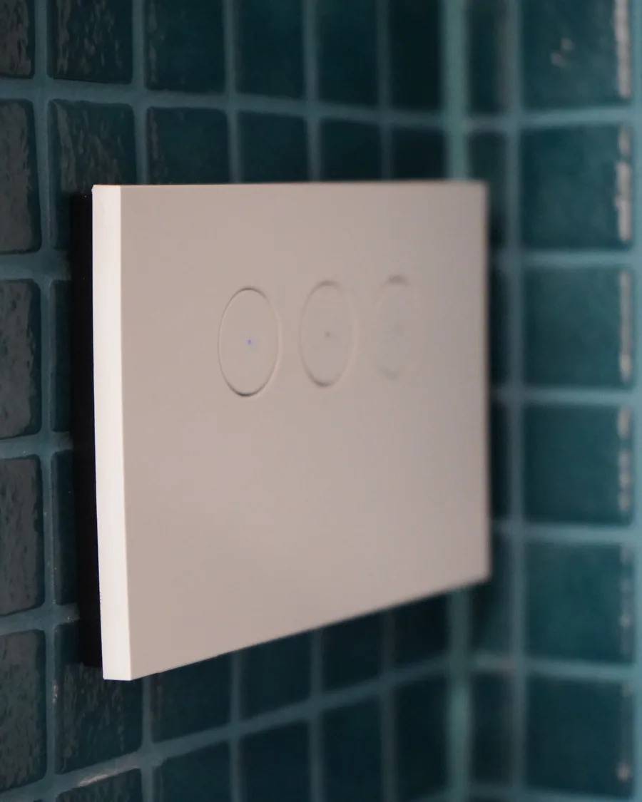 Close-up of a smart touch light switch installed on a mosaic-tiled wall