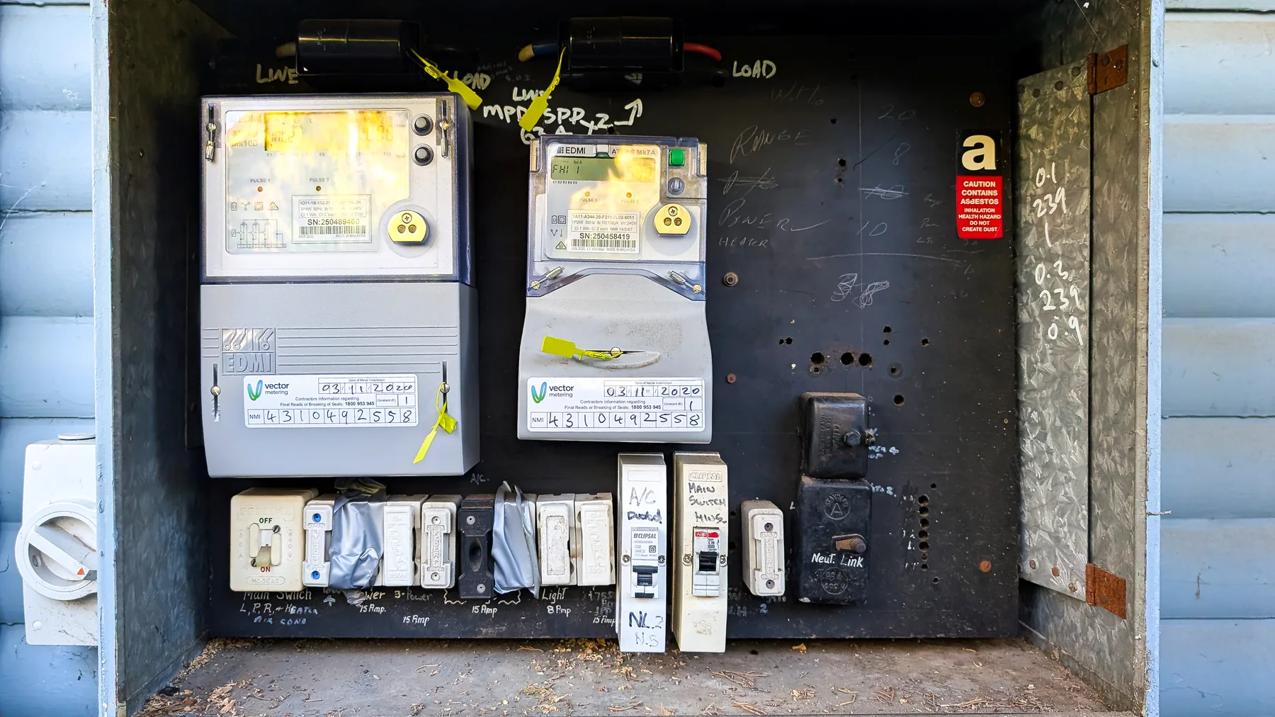 Ageing outdoor meter box with ceramic rewirable fuses and an asbestos warning label